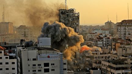 Une épaisse fumée se dégage d'un immeuble de Gaza en train de s'écrouler après une frappe de l'armée israélienne, le 12 mai 2021. (QUSAY DAWUD / AFP)