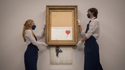 "L'Amour est dans la poubelle", une œuvre de l'artiste britannique Banksy, est présentée avant une vente aux enchères de la maison Sotheby's, le 3 septembre 2021, à Londres. (TOLGA AKMEN / AFP)