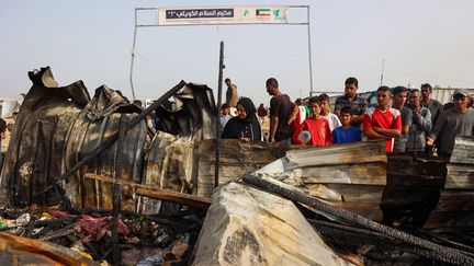 Des Palestiniens rassemblés sur le site d'une frappe israélienne sur un camp de personnes déplacées à Rafah, le 27 mai 2024. (EYAD BABA / AFP)