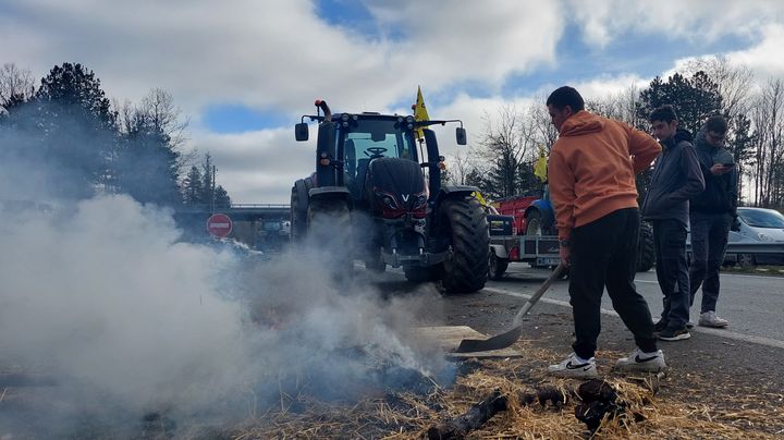 Des agriculteurs entretiennent les flammes d'un brasier, le 23 janvier 2024, sur l'A62 près d'Agen (Lot-et-Garonne). (FABIEN MAGNENOU / FRANCEINFO)