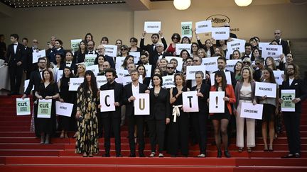 Des membres du collectif Cut ! (Cinéma uni pour la transition), qui réunit 400 professionnels du cinéma, ont voulu inciter avec leurs pancartes le cinéma à devenir plus responsable vis-à-vis de la planète. Parmi eux, on peut apercevoir au premier rang Cyril Dion, l'acteur belge Jérémie Renier ou encore le réalisateur Cédric Le Gallo (tout à gauche). (LOIC VENANCE / AFP)