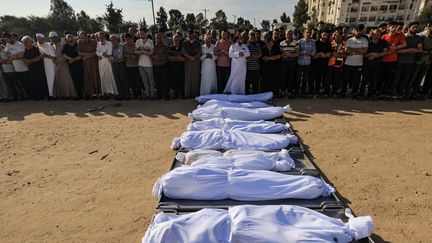 Des habitants prient devant les corps de la famille Agha, tués lors d'un bombardement de l'armée israélienne à Khan Younès dans la bande de Gaza, le 14 octobre 2023. (MAHMUD HAMS / AFP)