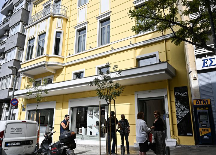 Des piétons se tiennent devant le bâtiment néoclassique du musée Maria Callas, dans le centre d'Athènes, lors de son ouverture officielle le 25 octobre 2023. (THEOPHILE BLOUDANIS / AFP)