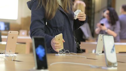 Une&nbsp;cliente observe un smartphone, dans un Apple Store de Paris, le 25 septembre 2015. (JACQUES DEMARTHON / AFP)