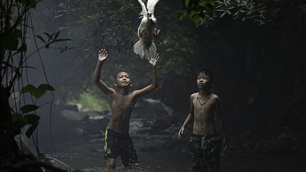 Deux enfants tentent d'attraper un canard dans la chute d'une cascade &agrave; Nang Khai, en Tha&iuml;lande.&nbsp;National Geographic Contest. (SARAH WOUTERS)