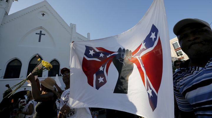 Un homme manifeste lors d'une marche en hommage aux victimes de la tuerie raciste de Charleston, le 20 juin 2015. Sur le tissu, une main noire se referme sur le drapeau conf&eacute;d&eacute;r&eacute;, consid&eacute;r&eacute; comme un symbole s&eacute;gr&eacute;gationniste.&nbsp; (BRIAN SNYDER / REUTERS)