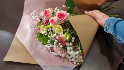 Un fleuriste emballe un bouquet de fleurs.&nbsp; (AURÉLIE LAGAIN/Radio France)