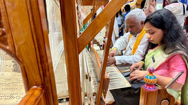 Les savoir-faire indiens sont présentés à la Maison de l'Inde. Ici, un père et sa fille travaillent sur un métier à tisser, utilisé pour fabriquer des tenues traditionnelles. (APOLLINE MERLE / FRANCEINFO SPORT)