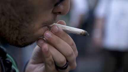 Un homme tire sur un joint de marijuana, &agrave; Montevideo (Uruguay), lors d'une manifestation pour la l&eacute;galisation, le 10 d&eacute;cembre 2013.&nbsp; (PABLO PORCIUNCULA / AFP)