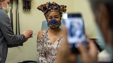 Une homme photographie sa fille qui se fait vacciner contre le Covid-19, le 2 avril 2021 à Louisville (Etats-Unis). (JON CHERRY / GETTY IMAGES NORTH AMERICA / AFP)