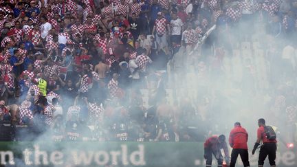 Le personnel du stade retire les fumigènes lancées sur la pelouse de Saint-Etienne, le 17 juin 2016. (PHILIPPE DESMAZES / AFP)