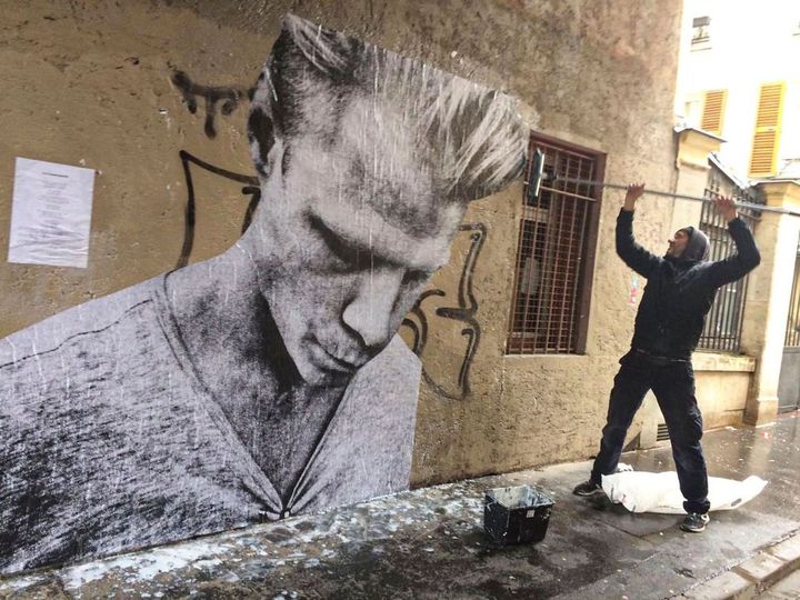 Le photographe Étienne Racine collant une de ces photographies sur un mur d'Arles en vue des Rencontres de la photographie. (ETIENNE RACINE)