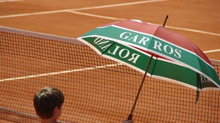 Un ramasseur de balles tenant un parapluie pour faire de l'ombre sur un court de Roland-Garros, porte d'Auteuil à Paris. Photo d'illustration. (PIERRE NEVEUX / RADIO FRANCE)