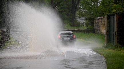 Une voiture roule sur une route inondée par la montée de l'Ain, entre Tossiat et Montagnat (Ain), le 10 mai 2021. (MAXPPP)