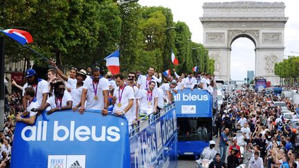 Trois bus &agrave; imp&eacute;riale, &agrave; bord desquels les athl&egrave;tes tricolores avaient pris place, ont fendu la foule mass&eacute;e sur les Champs-Elys&eacute;es, le 13 ao&ucirc;t 2012 &agrave; Paris. (MEHDI FEDOUACH / AFP)