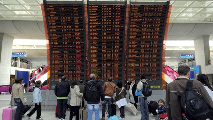 Des passagers devant un panneau d'affichage de l'aéroport Charles de Gaulle. Photo d'illustration. (MAXPPP)