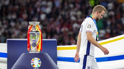 Harry Kane passe devant le trophée de l'Euro, qu'il ne soulèvera pas après la défaite anglaise, le 14 juillet 2024. (CHRISTIAN CHARISIUS / AFP)