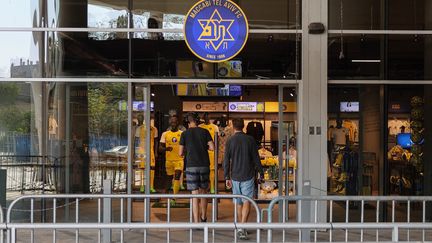 Deux hommes entrent dans un magasin officiel de l'équipe de football israélienne Maccabi Tel Aviv, au stade Bloomfield de Tel Aviv, le 8 novembre 2024. (JACK GUEZ / AFP)