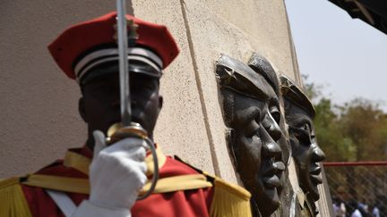 Un membre de la garde d'honneur se tient sous la statue de bronze de l'ancien président du Burkina Faso, Thomas Sankara, le jour de l'inauguration de son mémorial au Conseil de l'Entente de Ouagadougou, le 2 mars 2019. (ISSOUF SANOGO / AFP)