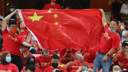 Des supporters chinois agitent leur drapeau durant le match de qualification à la Coupe du monde 2022 entre la Chine et l'Arabie saoudite, à Jeddah, le 12 octobre 2021. (AFP)