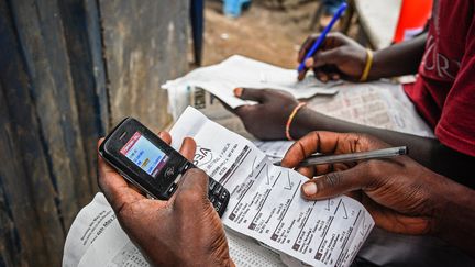 Le&nbsp;6 mai 2018 à Kampala, en Ouganda, un homme parie sur des matchs de football européens avec un téléphone portable dans un magasin de paris sportifs. (ISAAC KASAMANI / AFP)