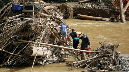 Après le passage d'un ouragan en octobre 2017, des personnes marchent parmi des débris pour accéder à une rivière à Porto Rico. (RICARDO ARDUENGO / AFP)