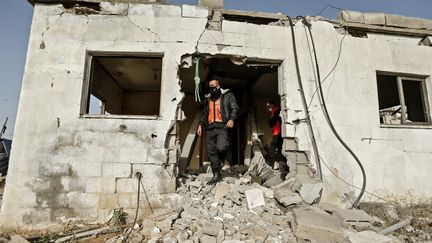 Des membres de la défense civile palestinienne inspectent une maison à Gaza, le 15 décembre 2020, après un bombardement de l'artillerie israélienne. (MAHMUD HAMS / AFP)