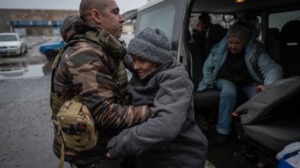 Une femme est sortie d'un véhicule par un membre d'une équipe d'évacuation, le 27 février 2023, à Koupiansk (Ukraine). (ANDRES GUTIERREZ / ANADOLU AGENCY / AFP)