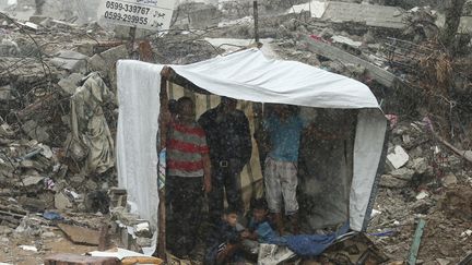 Des Palestiniens s'abritent de la pluie sous un abri de fortune dress&eacute; au milieu des d&eacute;combres &agrave; Gaza (Palestine), le 19 octobre 2014. ( MOHAMMED SALEM / REUTERS)