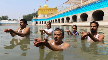 Des fidèles hindous prennent&nbsp;un bain sacré et prient le dieu du soleil pendant l'éclipse, dans un temple à Amritsar (Inde). (NARINDER NANU / AFP)