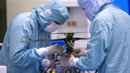 Des ingénieurs de la Nasa travaille sur l'hélicoptère "Ingenuity", avant son envoi sur mars, au Kennedy Space Center, en Floride, le 10 mars 2020.&nbsp; (CORY HUSTON / NASA / AFP)