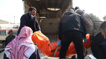 Des réfugiés syriens en Turquie chargent des corps dans des camionnettes qui prennent la direction de la Syrie, le 12 février 2023. (AHMAD AL-ATRASH / AFP)