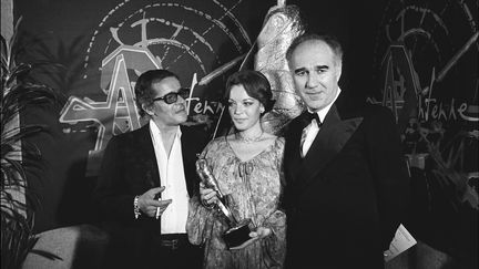 Les acteurs Serge Reggiani, à gauche, Romy Schneider, au centre avec le César et Michel Piccoli, au Palais des congrès, en 1976 pour la première cérémonie des César. (AFP)