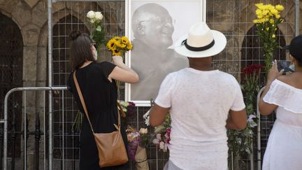 Des Sud-Africains déposent des fleurs devant un portrait de Desmond Tutu, au Cap, le 26 décembre 2021.&nbsp; (RODGER BOSCH / AFP)