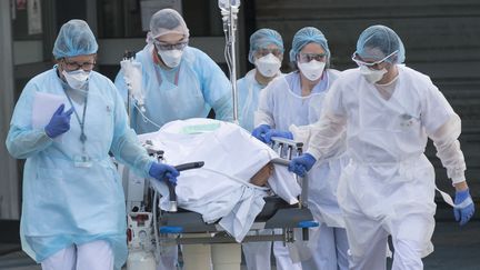 Des soignants conduisent un patient vers un hélicoptère médicalisé, le 17 mars 2020, à l'hôpital de Mulhouse (Haut-Rhin). (SEBASTIEN BOZON / AFP)