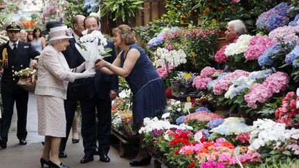 Elizabeth II se voit offrir des fleurs au march&eacute; de l'&icirc;le Saint-Louis, &agrave; Paris, le 7 juin 2014. (FRANCOIS MORI / POOL / AFP)