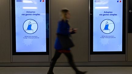 Une femme passe devant un message d'information sur le coronavirus à la gare de Rennes. (DAMIEN MEYER / AFP)