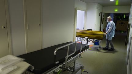 Un employé des pompes funèbres sort le cercueil d'une victime du Covid-19, le 5 avril 2020, à l'hôpital de Mulhouse (Haut-Rhin). (SEBASTIEN BOZON / AFP)