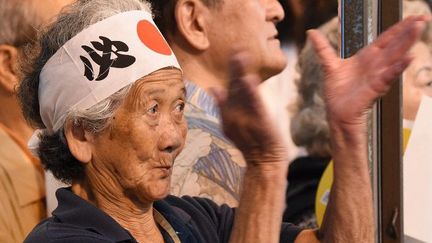 Une Japonaise portant un bandeau avec le drapeau national applaudit le Premier ministre japonais Shinzo Abe en meeting éléctoral à Tokyo, le 9 juillet 2016. (TORU YAMANAKA / AFP)