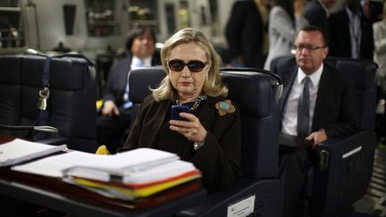 Hillary Clinton, alors secrétaire d'Etat, consulte son téléphone à bord d'un avion au départ de Malte, le 18 octobre 2011. (KEVIN LAMARQUE / AP / SIPA)
