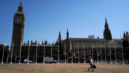 Illustration : un piéton marche sur l'herbe desséchée de Parliament Square, près de Big Ben, dans le centre de Londres, pendant une vague de chaleur extrême le 18 juillet 2022. (NIKLAS HALLE'N / AFP)