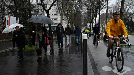 En raison de la&nbsp;grève dans les transports en commun,&nbsp;des personnes marchent ou roulent sous la pluie, le 16 décembre 2019, porte de Vanves, à Paris. (DOMINIQUE FAGET / AFP)