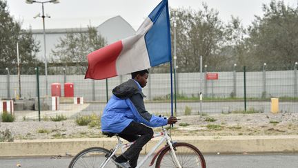 Un jeune migrant de la "jungle" de Calais tient un drapeau français. (PHILIPPE HUGUEN / AFP)