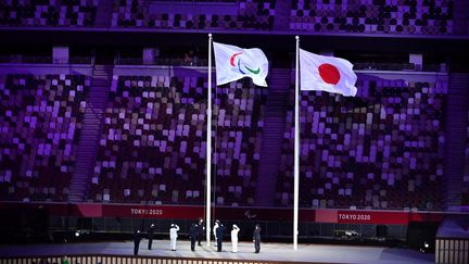 Le drapeau paralympique est hissé à côté de celui du Japon lors de la cérémonie d'ouverture des Jeux paralympiques de Tokyo, le 24 août 2021. (CHARLY TRIBALLEAU / AFP)