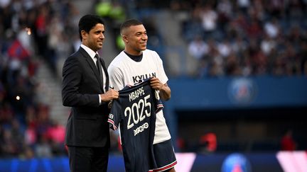 L'attaquant du Paris Saint-Germain Kylian Mbappé pose avec le président du club Nasser Al-Khelaifi, après l'annonce de son maintien au PSG jusqu'en 2025 avant le match de L1 entre Paris et Metz au stade du Parc des Princes, le 21 mai 2022. (ANNE-CHRISTINE POUJOULAT / AFP)