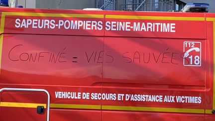 Garé devant l’entrée les urgences réservées aux suspicions de Covid-19 au CHU de Rouen, un camion de pompier porte cette inscription en noire : "confiné = vies sauvées". (FANNY LECHEVESTRIER / RADIO FRANCE)