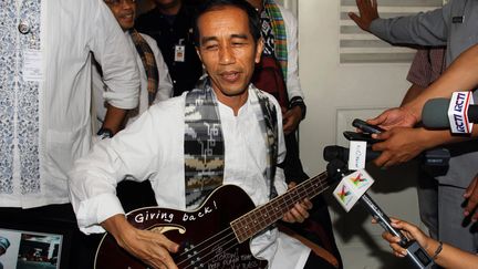 Le futur pr&eacute;sident indon&eacute;sien, Joko Widodo, et sa basse d&eacute;dicac&eacute;e par un membre du groupe Metallica. (STR / AFP)