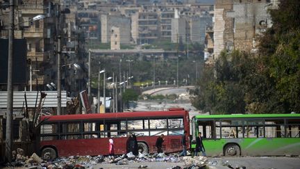 Des Syriens se prot&egrave;gent des snipers derri&egrave;re des autobus &agrave; Alep (Syrie), le 12 avril 2013. (DIMITAR DILKOFF / AFP)