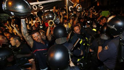 Des pompiers l&egrave;vent leur casque contre des policiers &agrave; Madrid&nbsp;jeudi 19 juillet.&nbsp; (SERGIO PEREZ / REUTERS)