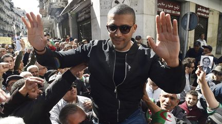 Khaled Drareni&nbsp; porté par des manifestants à Alger, le 6 mars 2020.&nbsp; (RYAD KRAMDI / AFP)